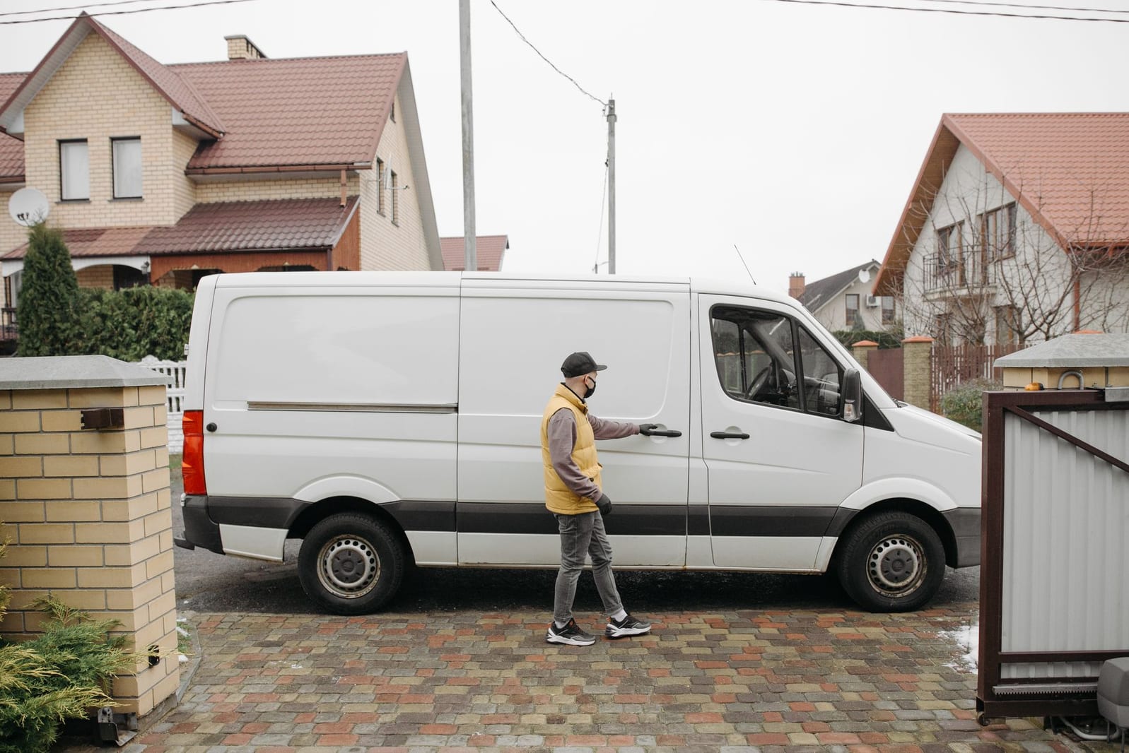 A plain white service van parked outside a property as a technician arrives for a job