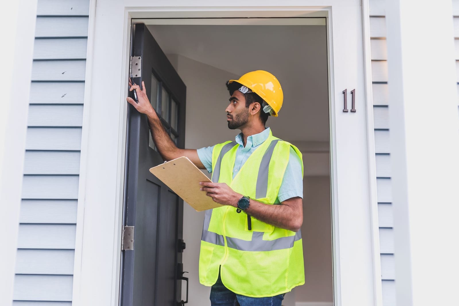 A pest-control inspector checking a door frame at a residential entrance